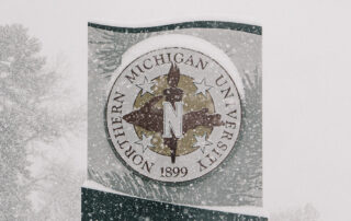 A Northern Michigan University sign on a snowy day.