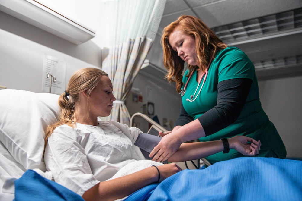 NMU nursing graduate takes vitals for female patient