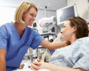 A hospital nurse comforts a patient awaiting surgery
