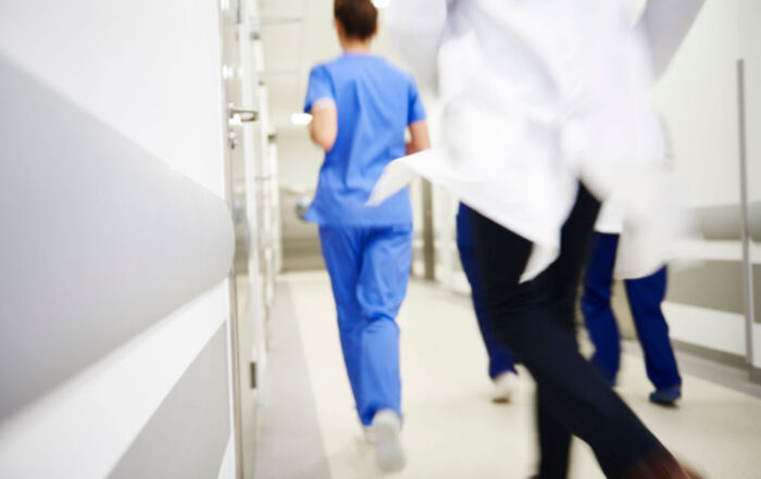 A nurse and a team of doctors run down a hospital hallway
