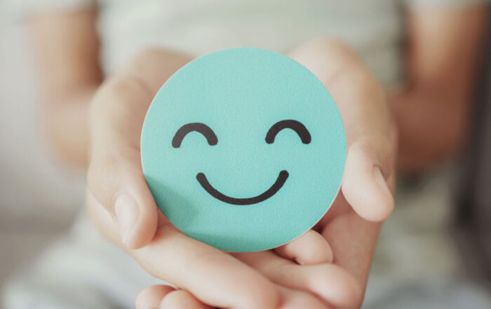 Person holds a smiling face in hands