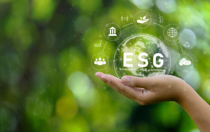 A sustainable business concept image of a hand holding a crystal globe with “ESG” against a blurred green background