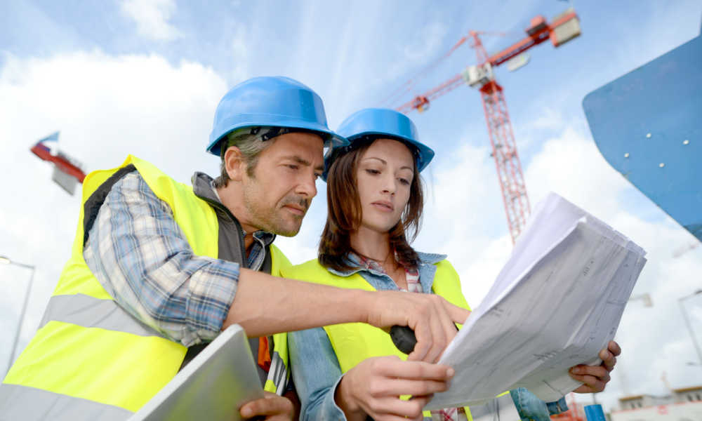A female construction manager consults with an engineer at a construction site.
