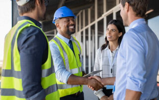 A team of construction engineers, managers, and architects meet at a construction site.