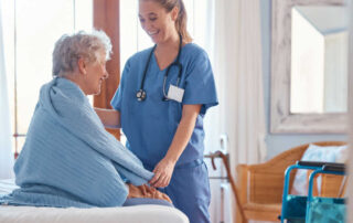 A smiling female nurse comforts an elderly patient.