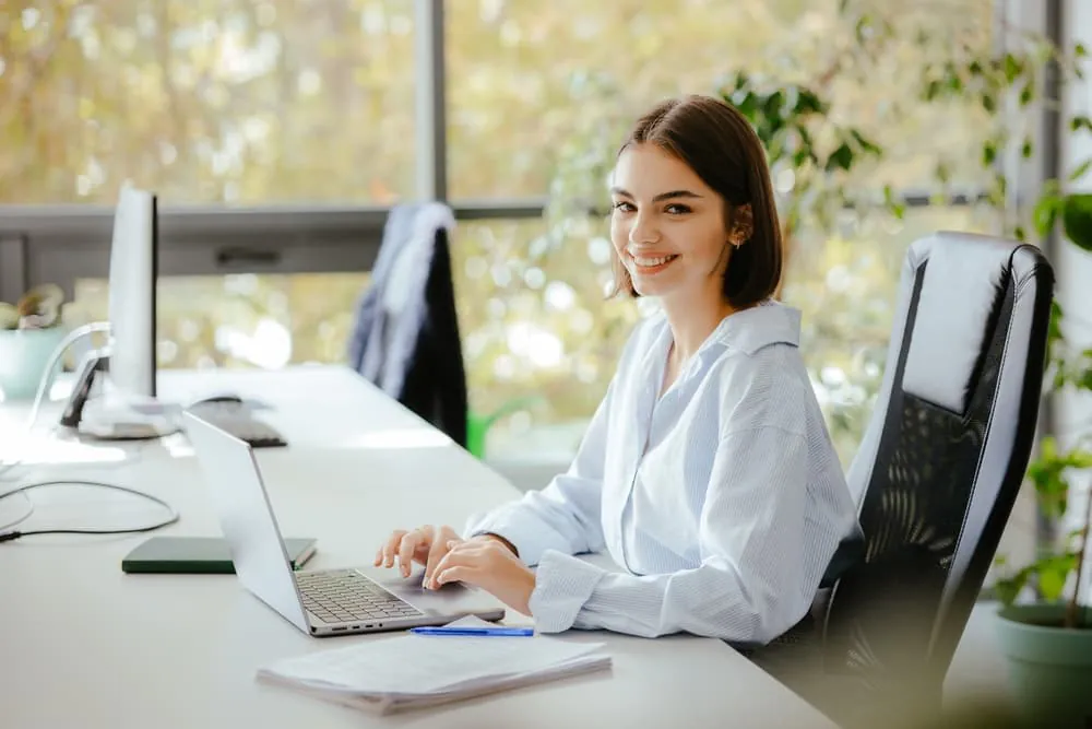 A city worker smiles while working on her office laptop