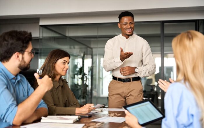 A smiling African-American business executive meets with his diverse team