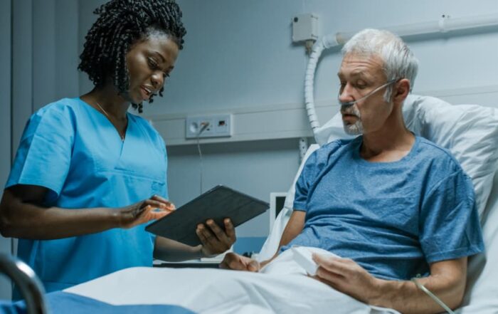 A nurse examines her elderly patient's chart at his hospital bedside.