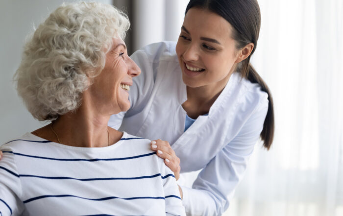 A caregiver comforts a smiling mature woman