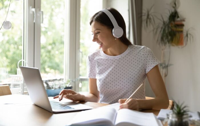 A smiling female college student studies an online lecture at home.